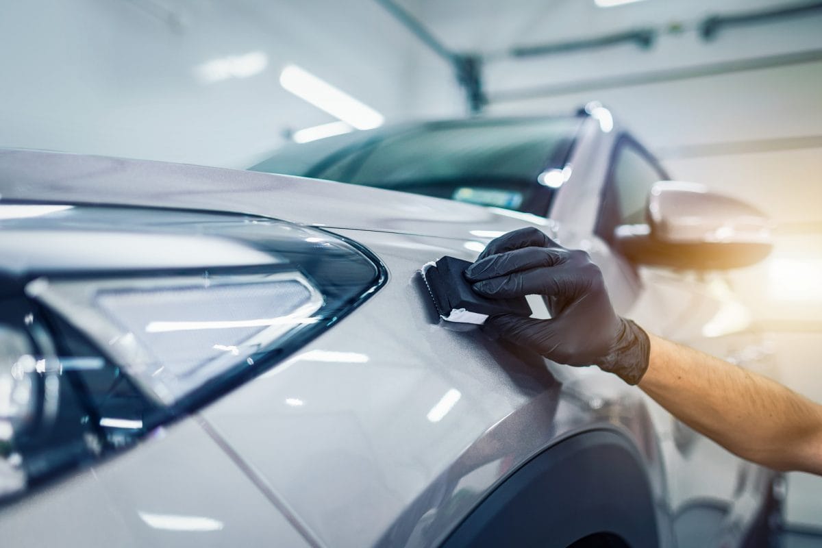 Gloved hand applying ceramic coating to the bonnet of a white car