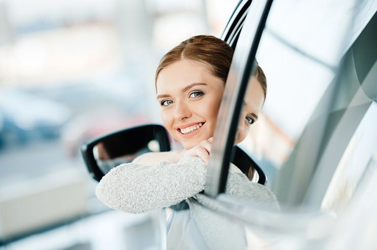 Smiling driver looking out of a car window on a sunny day