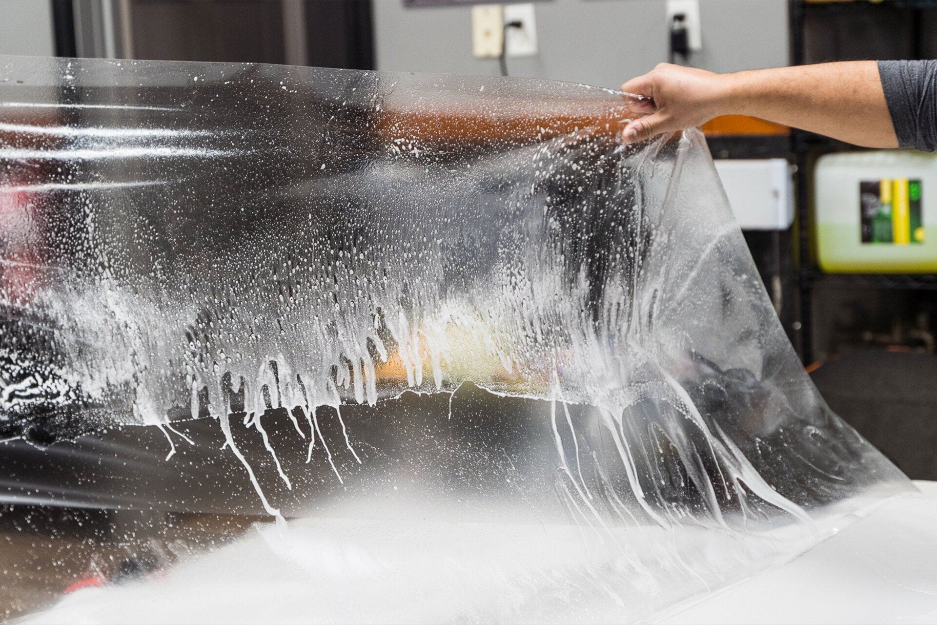 Installer stretching clear paint protection film before fitting it to a car panel
